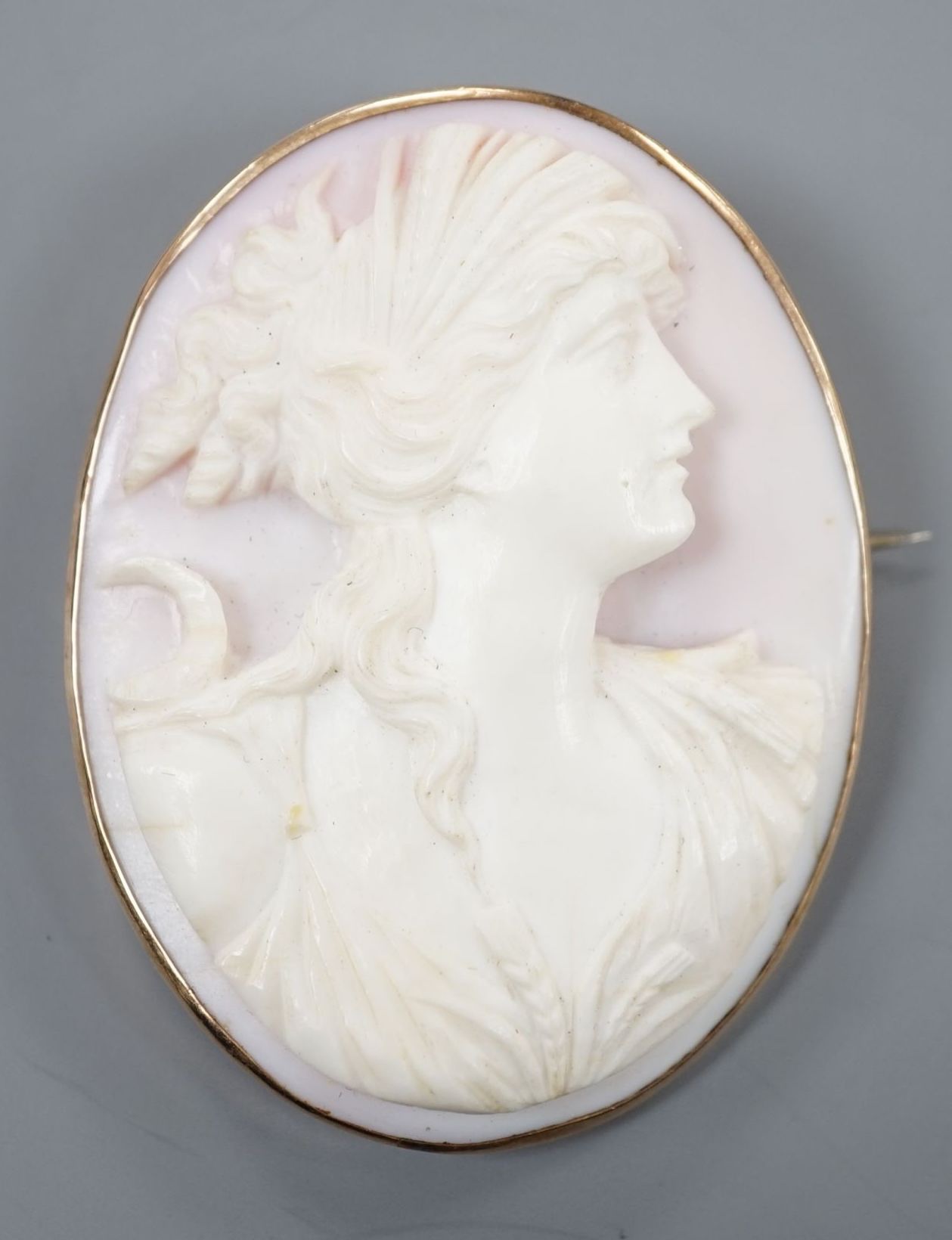 A yellow metal mounted oval cameo shell brooch, carved with the bust of a lady to sinister, 58mm .